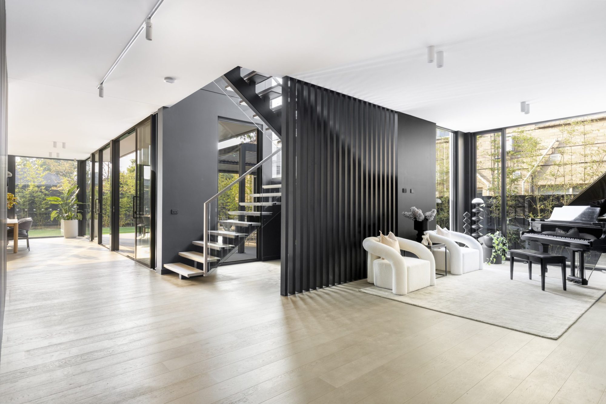 Living area with black battened staircase, Surrey Hills luxury home by Bluestar
